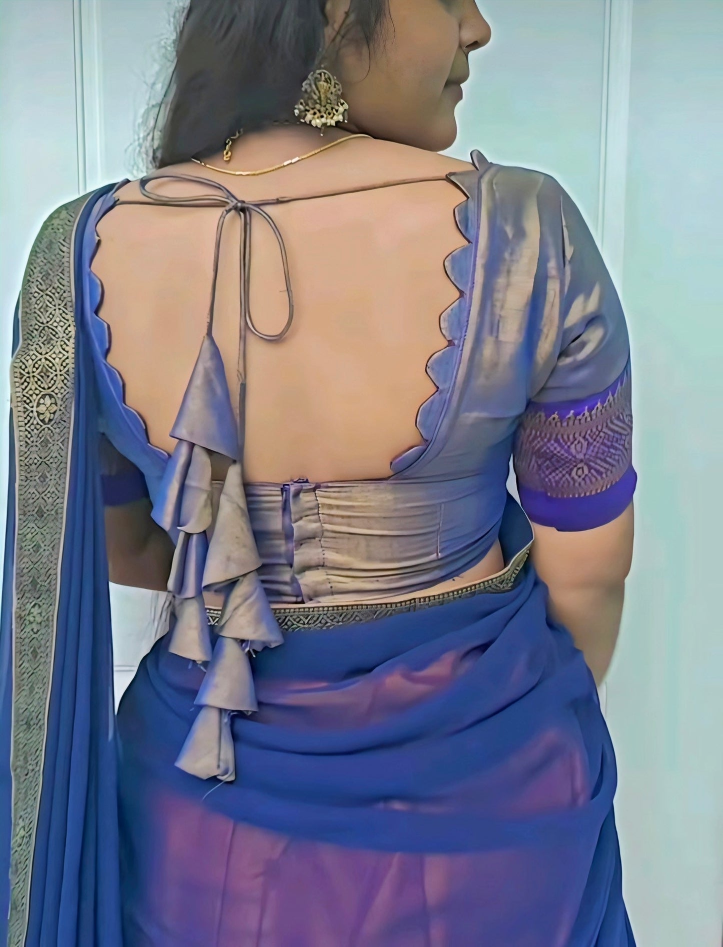 Woman wearing a blue saree with a beige blouse against a white background