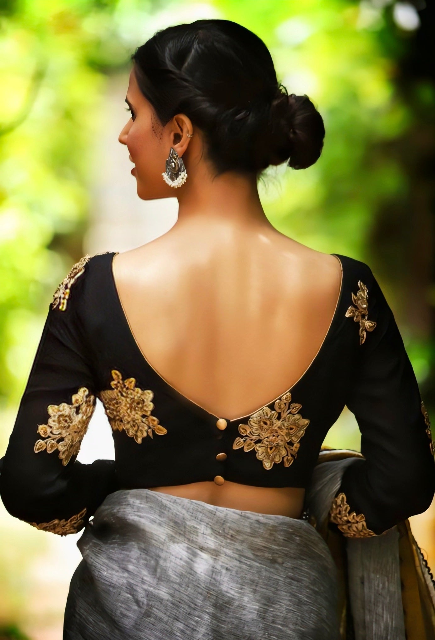 Black back neck blouse with golden floral embroidery and button closure, perfect for festive and party saree looks.