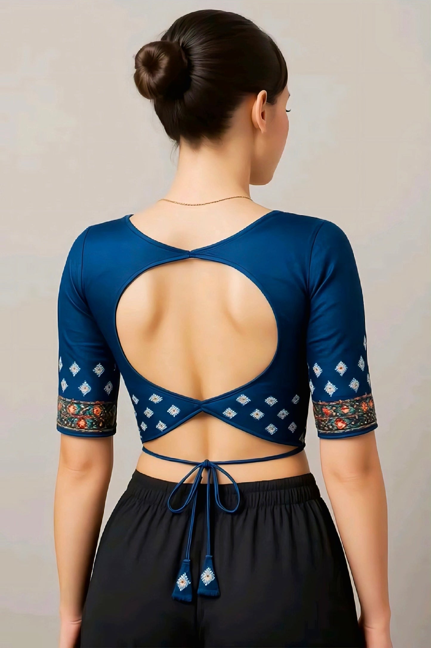 Navy blue blouse with round open back design, embroidered sleeves, and tie-up tassels, ideal for festive sarees.