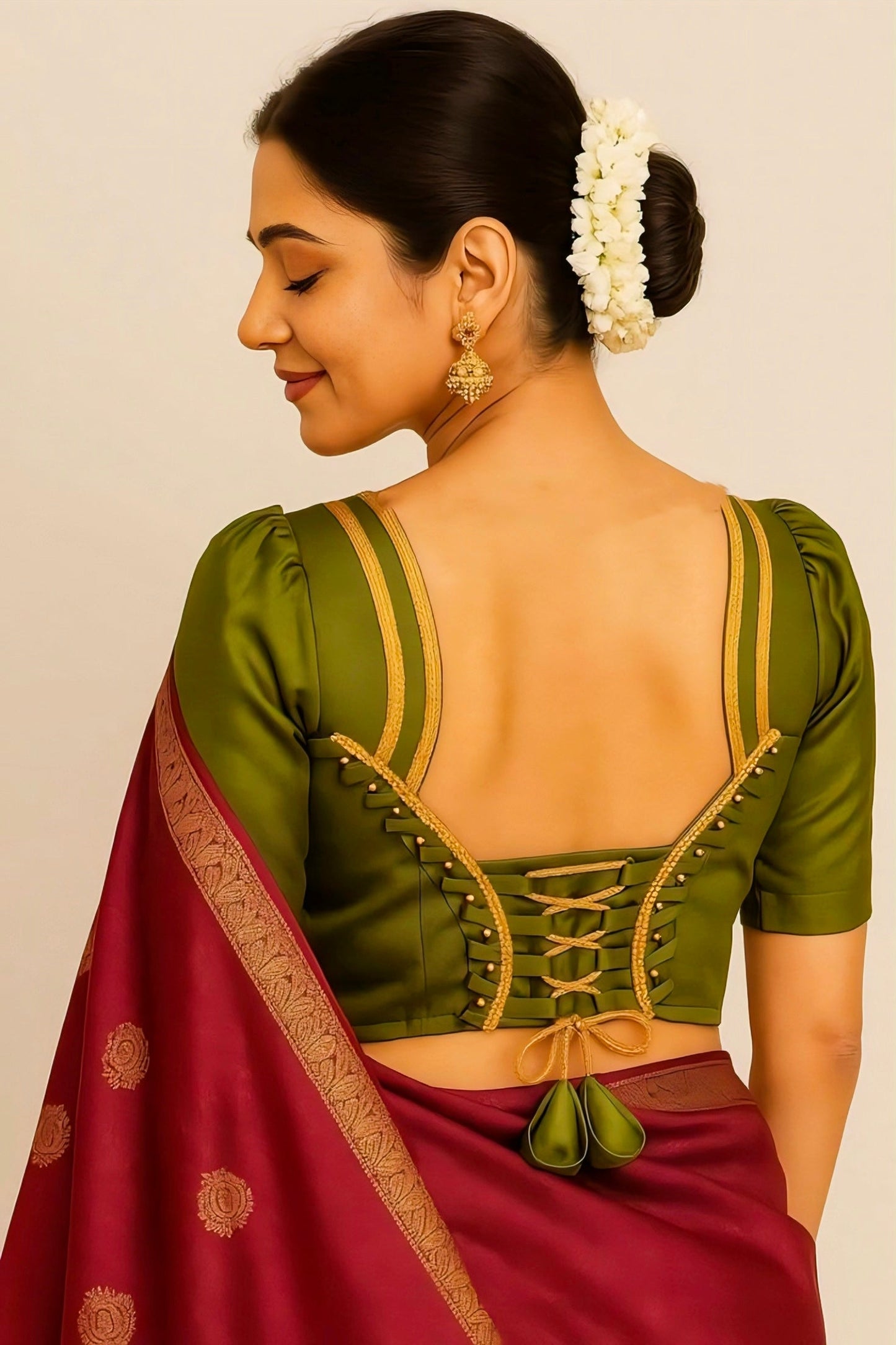 Woman wearing a green blouse with a maroon saree against a beige background