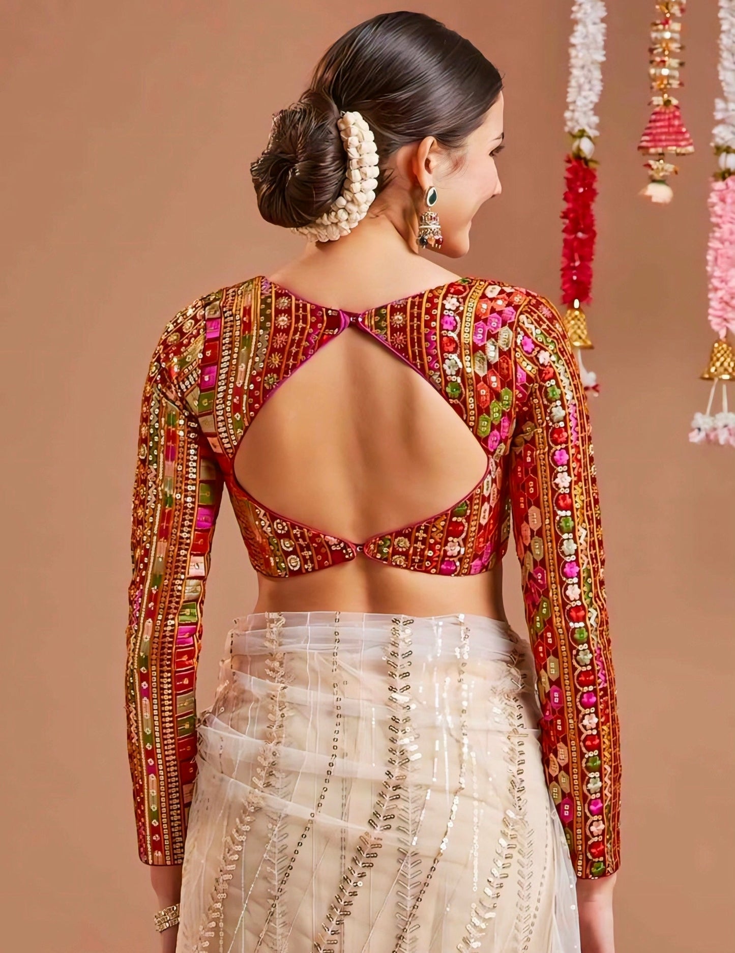 Woman wearing red mirror-work blouse with diamond-shaped back cut and long embroidered sleeves, ideal for festive and wedding wear.