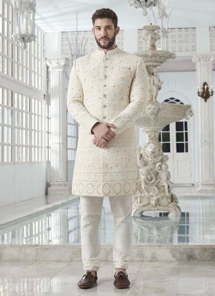 Man wearing royal engagement white dress for men with heavy embroidered sherwani and classic buttons, styled for a grand groom look