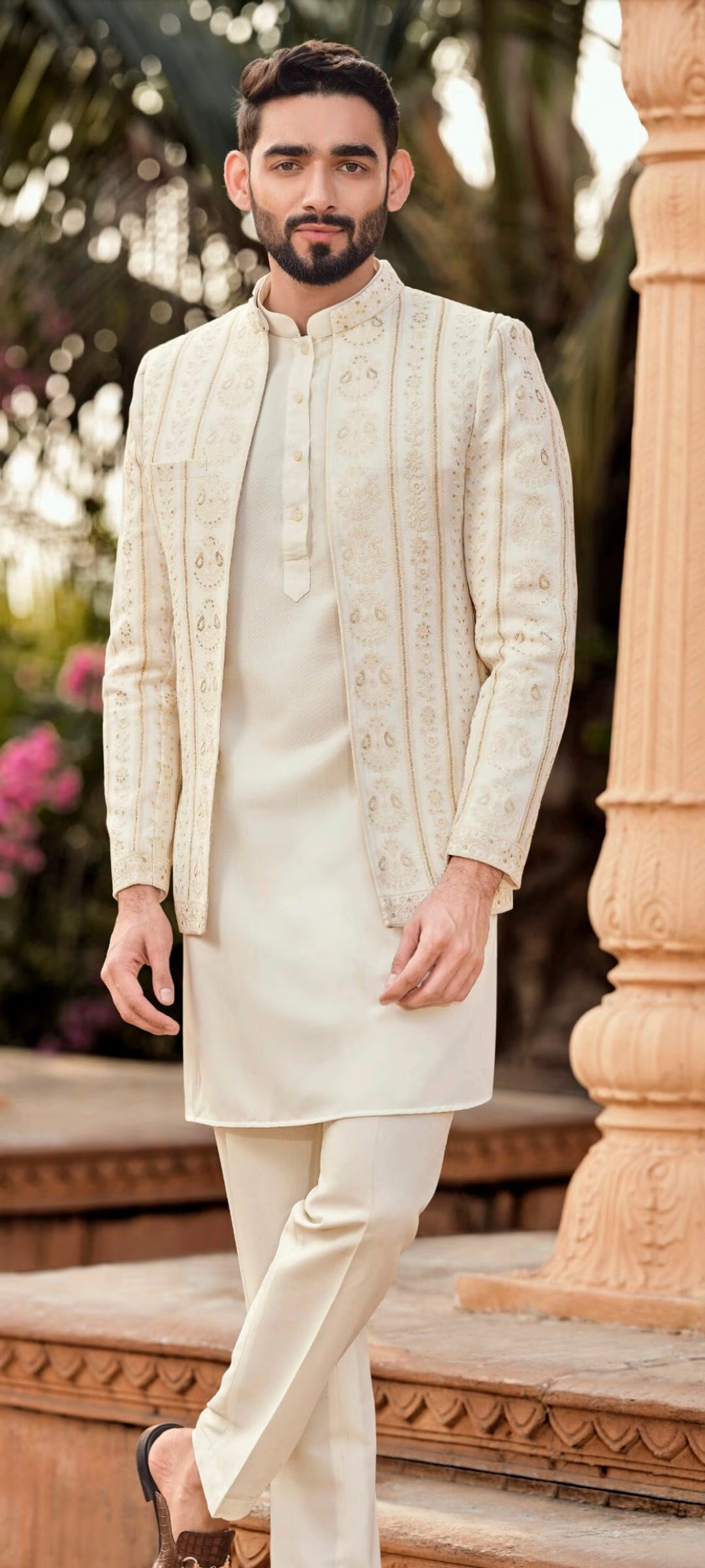 Man wearing elegant engagement white dress for men with embroidered jacket and kurta set, styled for a modern groom outdoor celebration