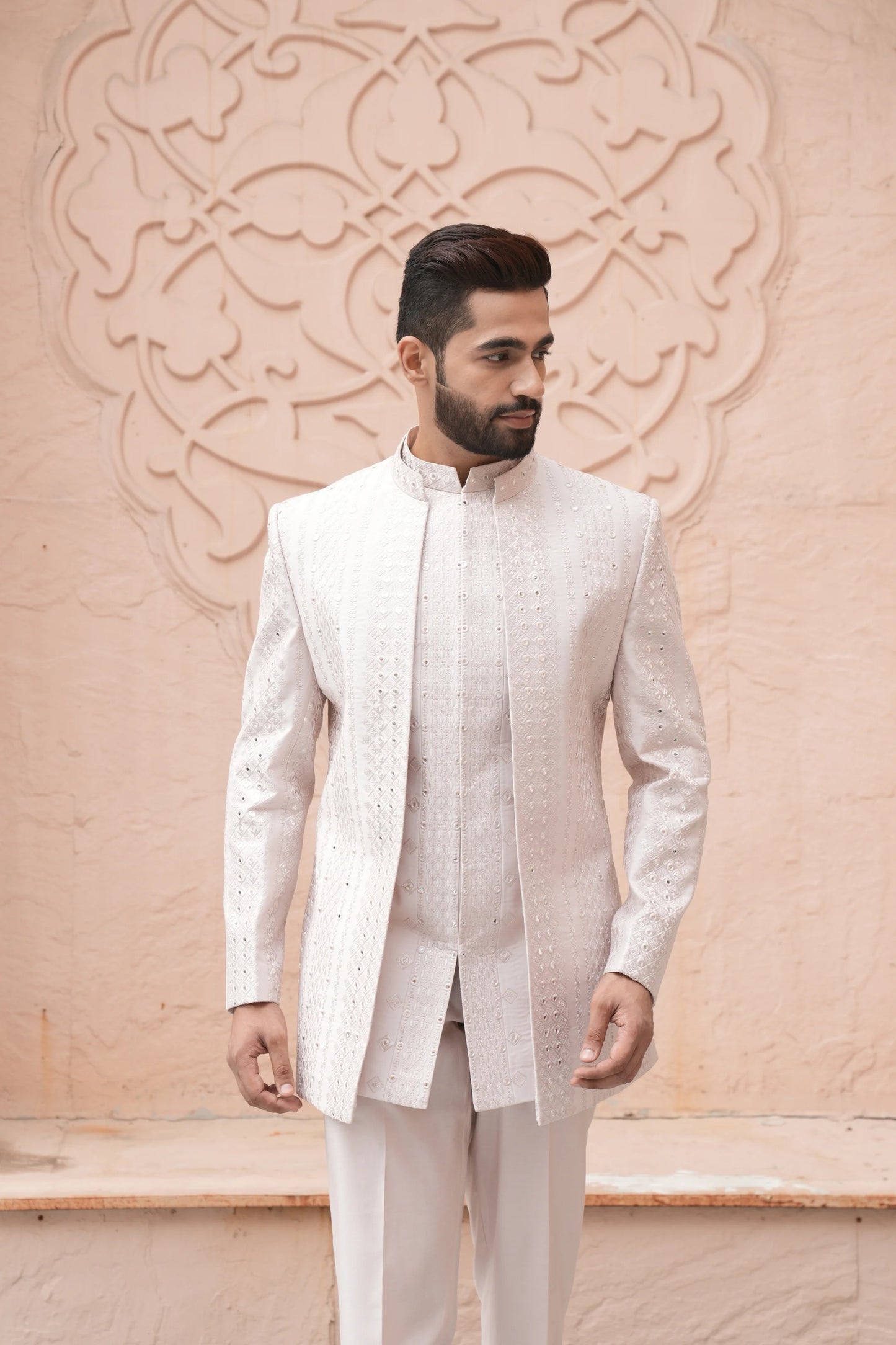 Man wearing classic engagement white dress for men with textured embroidery and mandarin collar, styled for a sophisticated groom look