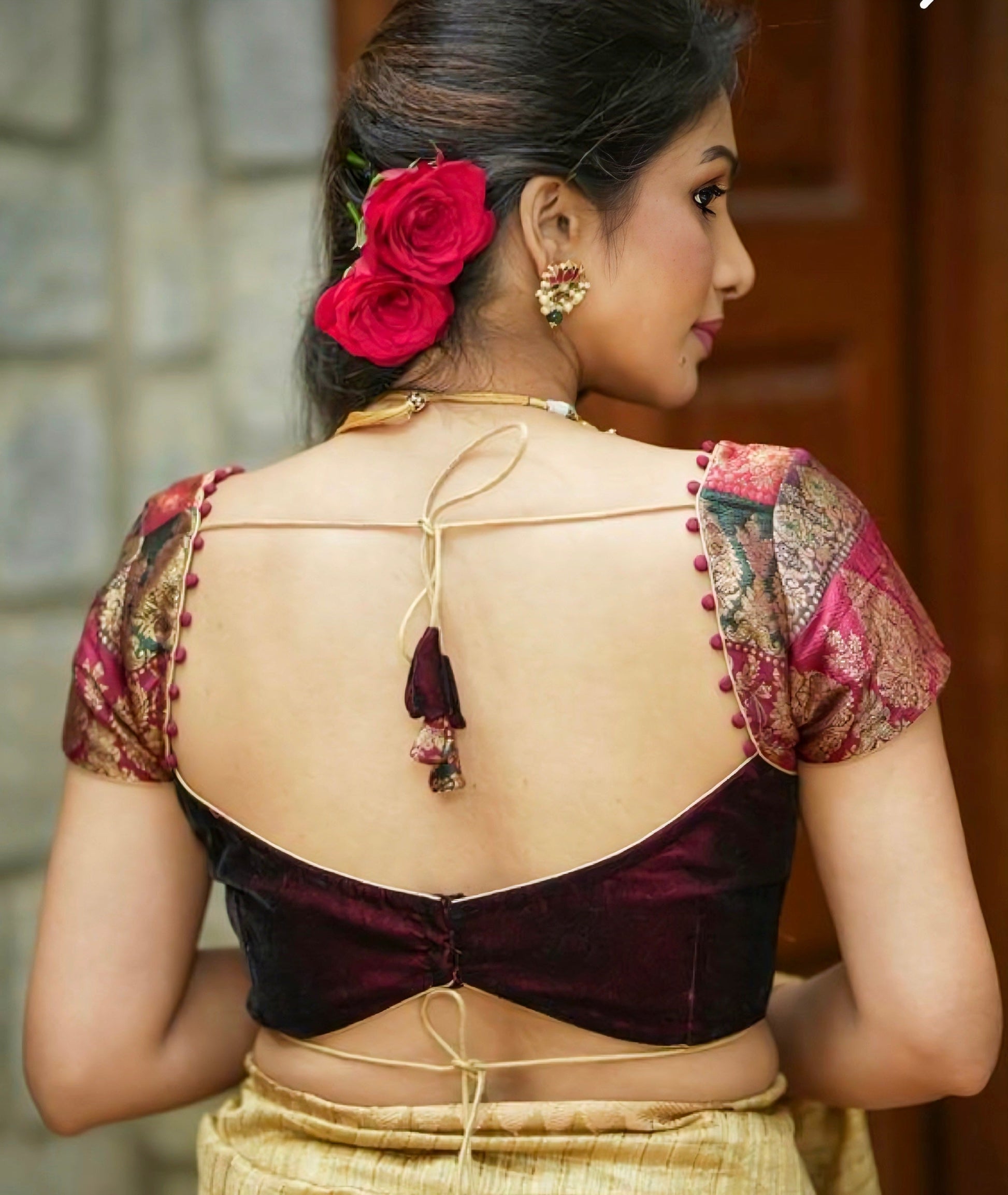 Woman wearing a traditional blouse with floral design and red roses in hair