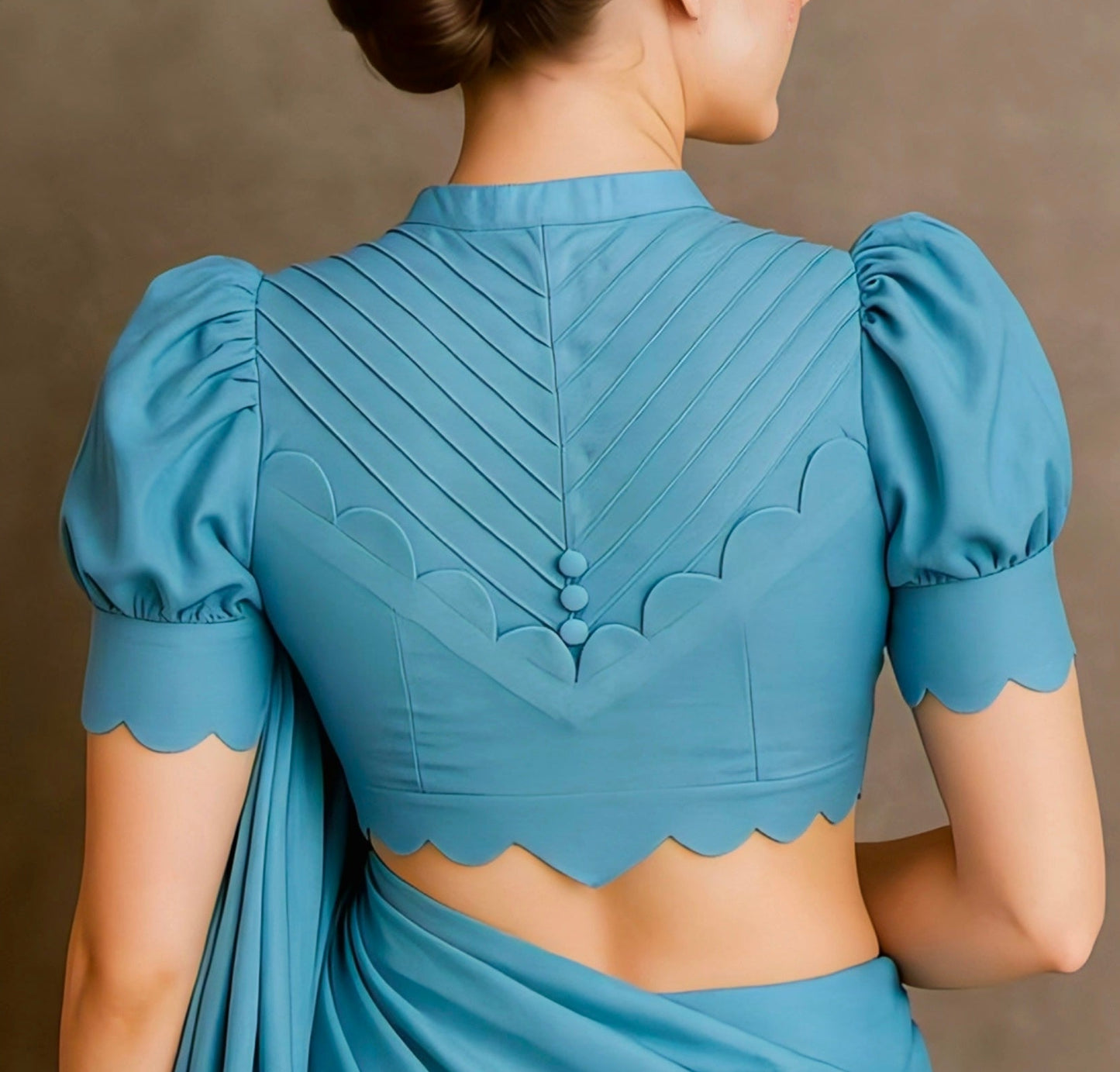 Sky blue blouse with pleated back, puff sleeves, scallop edges, and fabric buttons — modern saree blouse design for 2025 fashion trends.