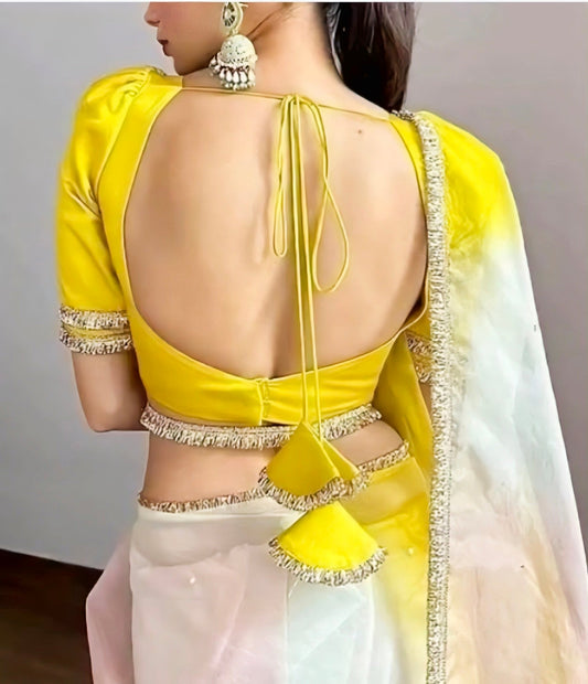 Yellow silk blouse with deep back design, tie-up tassels, and decorative borders — perfect for haldi and wedding saree looks.