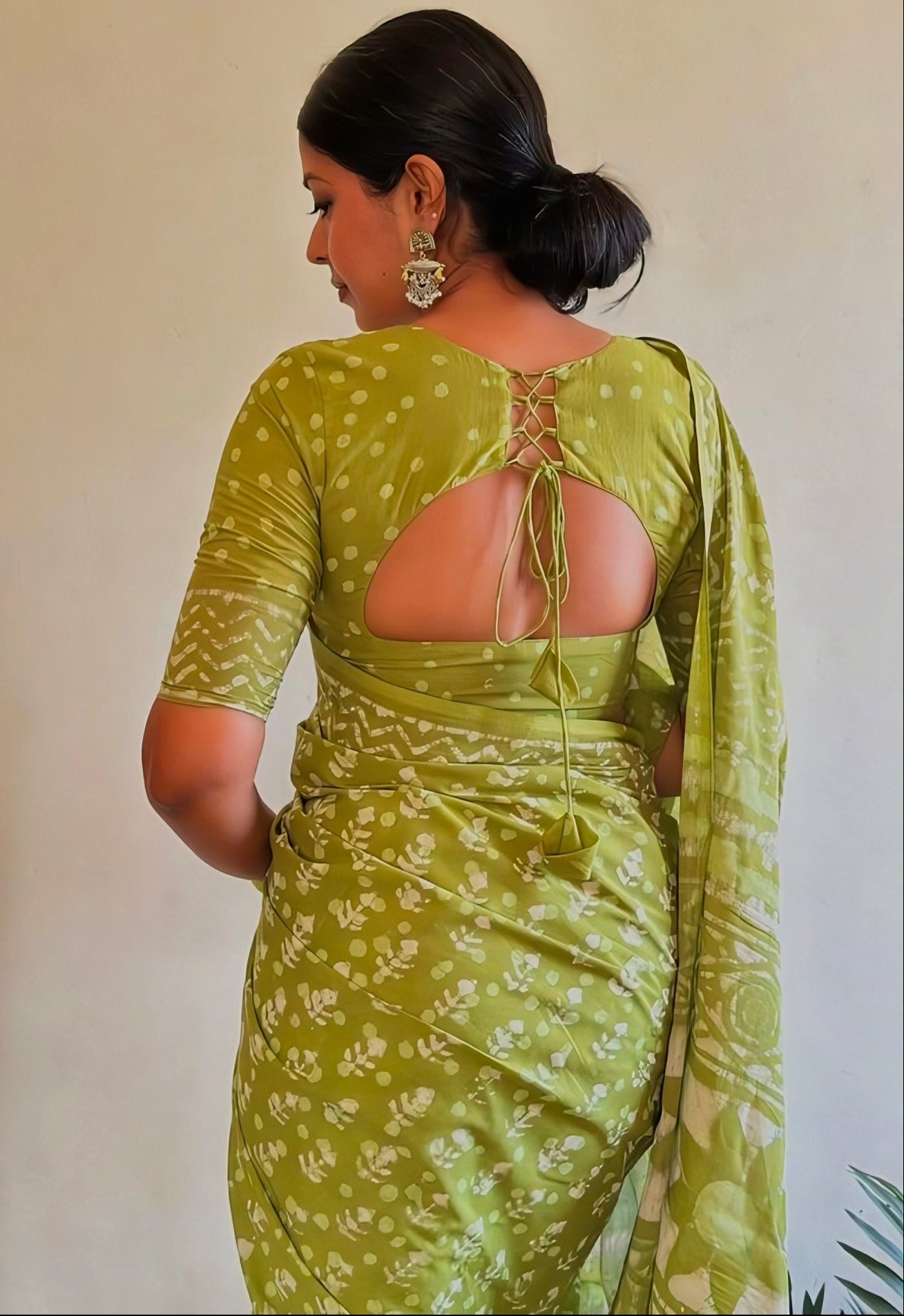 Olive green printed saree with matching back neck blouse featuring a rounded cutout and tie-up dori design. The elegant ethnic outfit offers a modern yet traditional look, perfect for festive and daytime occasions.