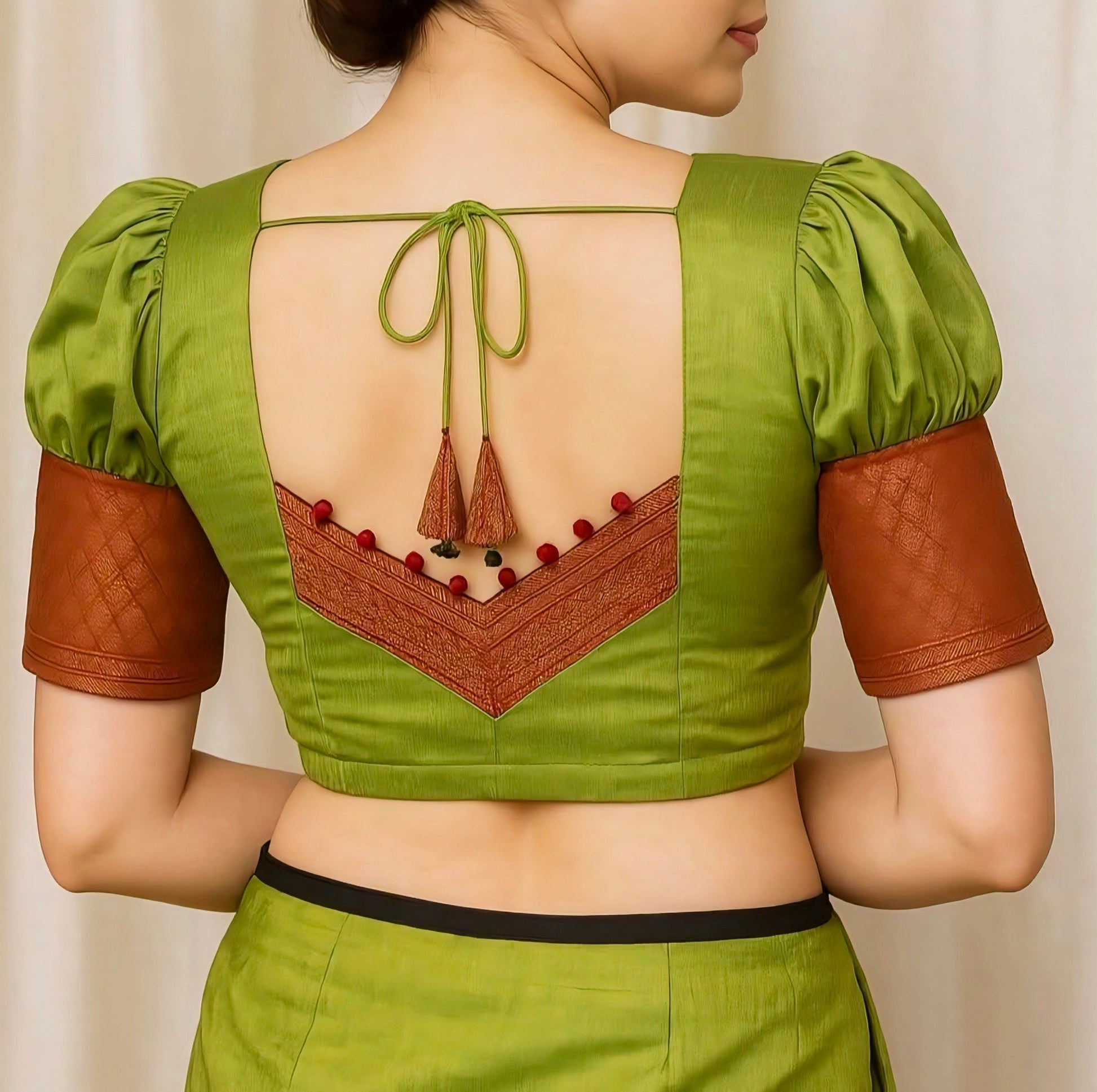 Green blouse with open back and brown accents on a plain background