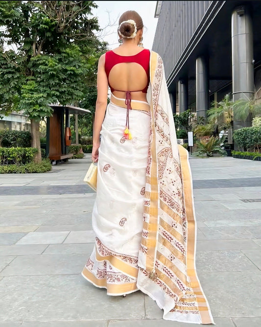 Woman wearing a red round back-neck blouse with tie-up detail paired with a white and gold embroidered saree, photographed from the back.