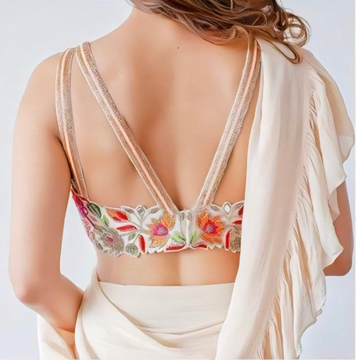 “Designer floral embroidered back-neck blouse with double straps in a pastel saree.”