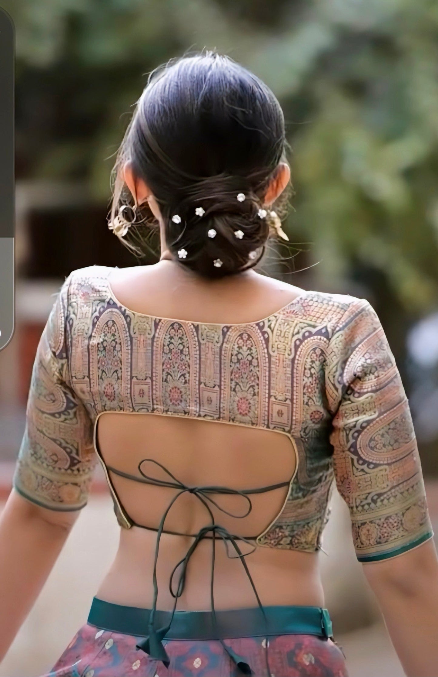Traditional printed back-tie blouse with half sleeves and open-back design styled with a bun hairstyle.