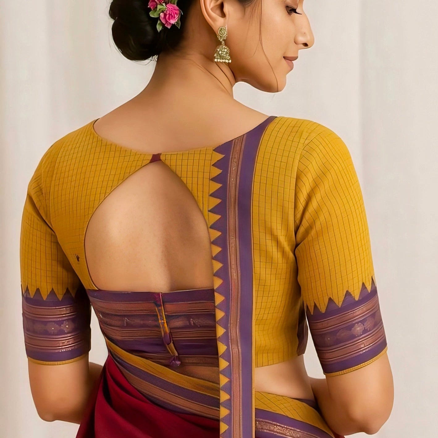 Traditional mustard yellow back-open blouse with geometric border design and keyhole cut-out, paired with a maroon saree.