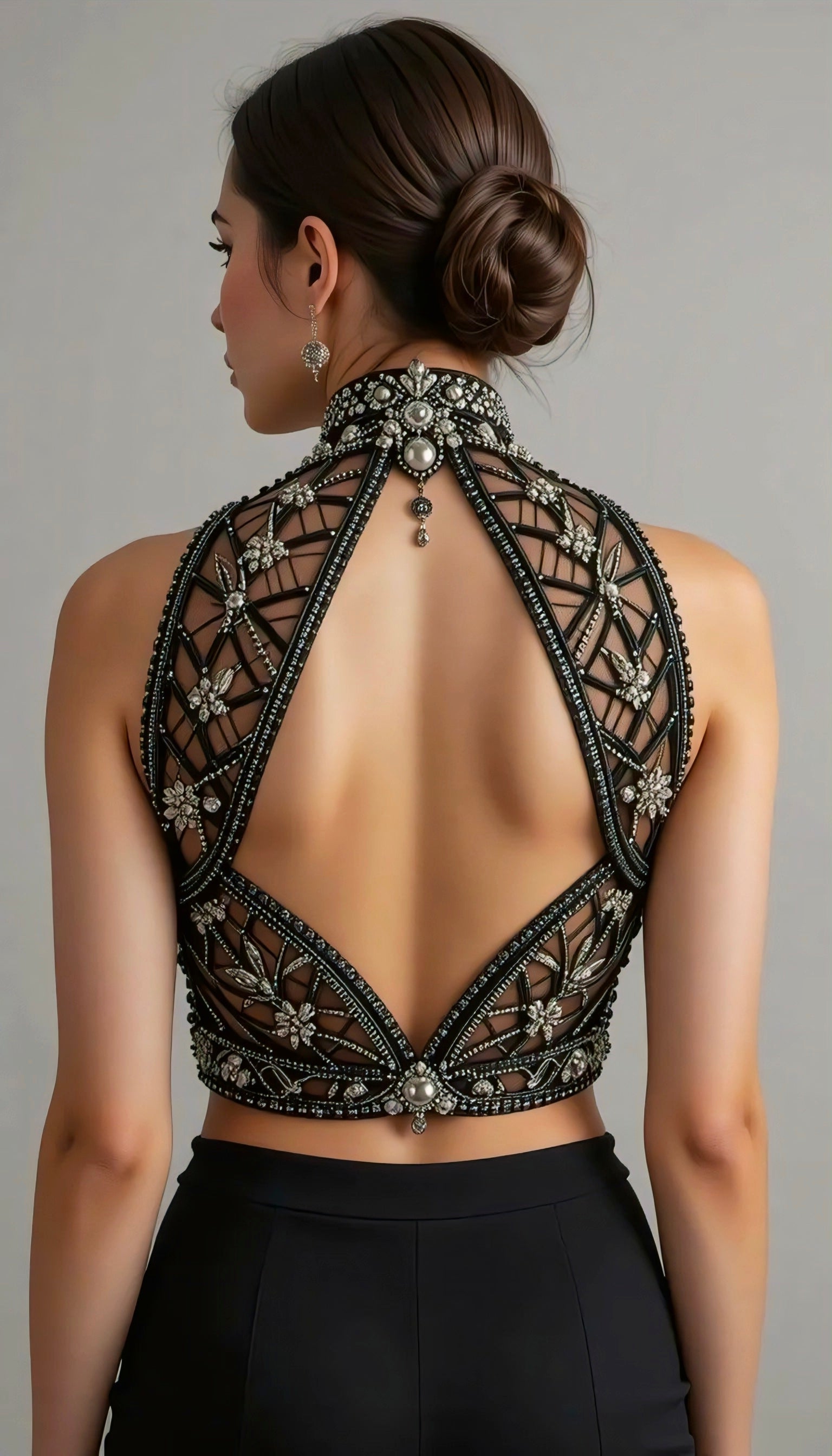 Back view of a black embellished halter-neck designer blouse featuring intricate beadwork, sheer mesh detailing, and a deep cut-out back.
