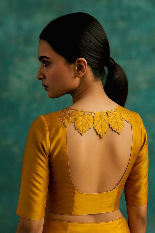 Mustard yellow blouse with deep U-back and 3D leaf appliqué design – modern festive and wedding wear blouse.