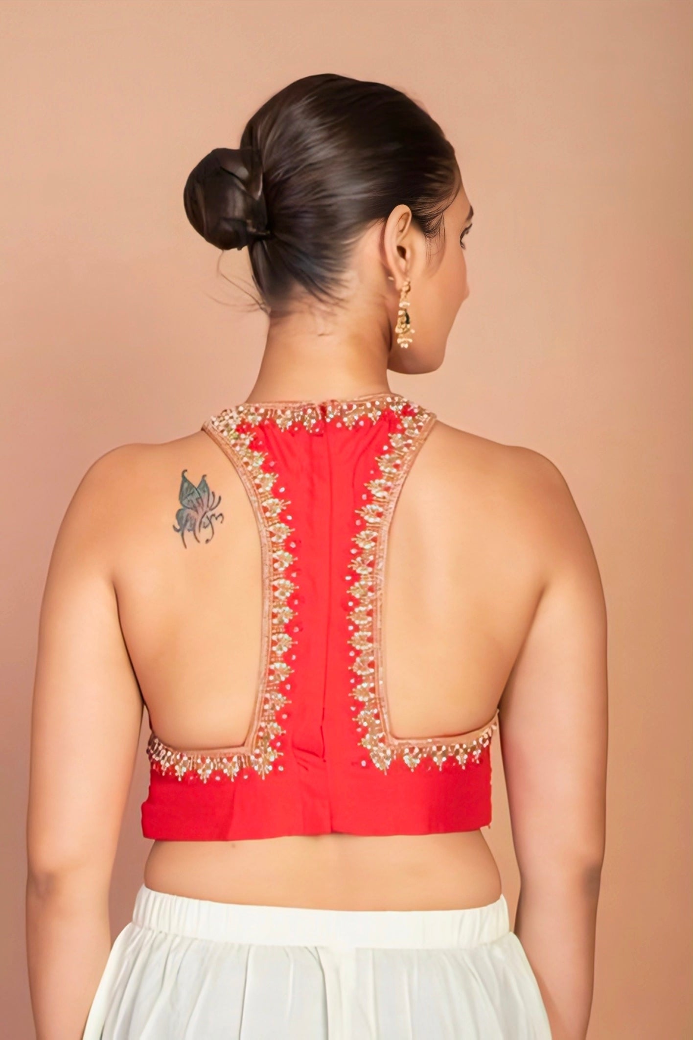 Woman wearing red halter-back embroidered blouse — designer saree blouse for festive and wedding looks.