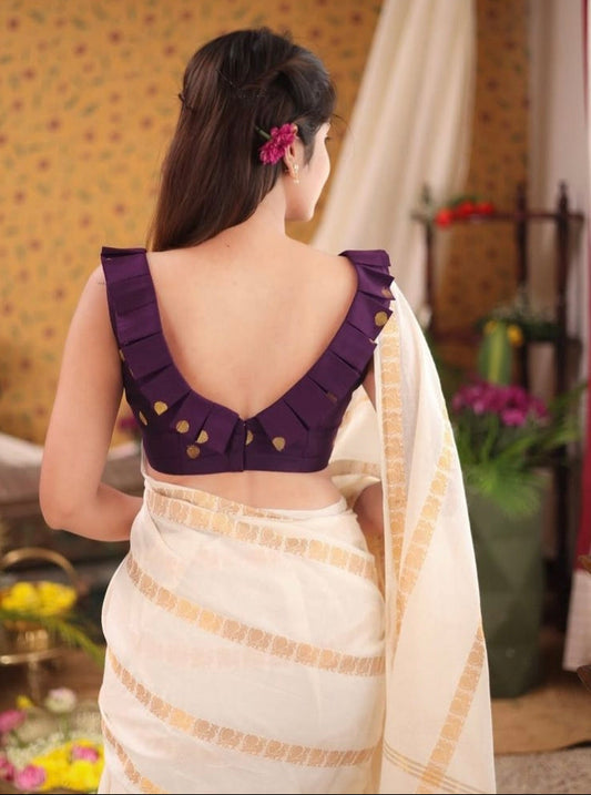 Woman wearing a purple pleated V-back blouse with gold dot design, paired with a white and gold traditional saree.