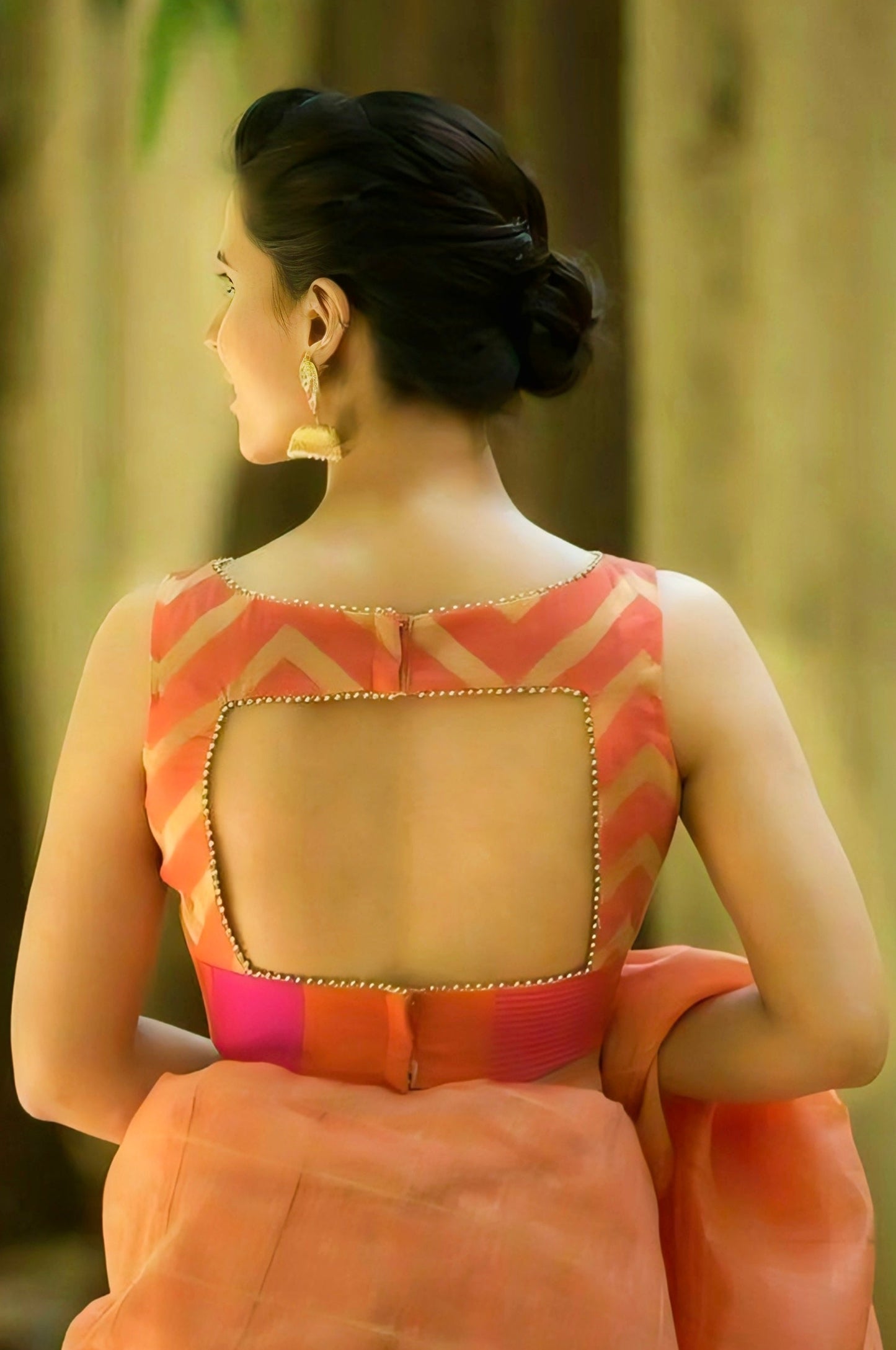 Woman wearing an orange silk blouse with square back cut and golden bead detailing — sleeveless ethnic saree blouse design.