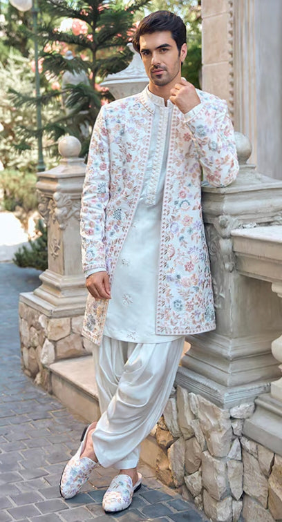 Man wearing elegant engagement white dress for men with pastel floral embroidered long jacket, kurta, and dhoti pants for a refined groom look