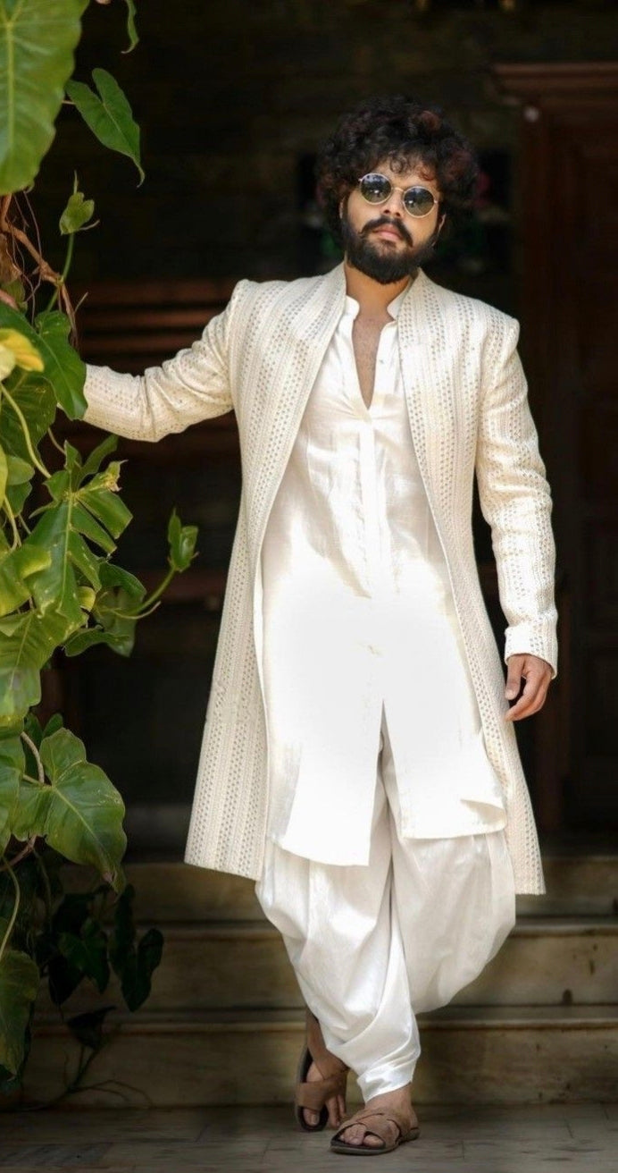 Engagement white dress for men with a long textured jacket paired with a white kurta and dhoti-style bottoms
