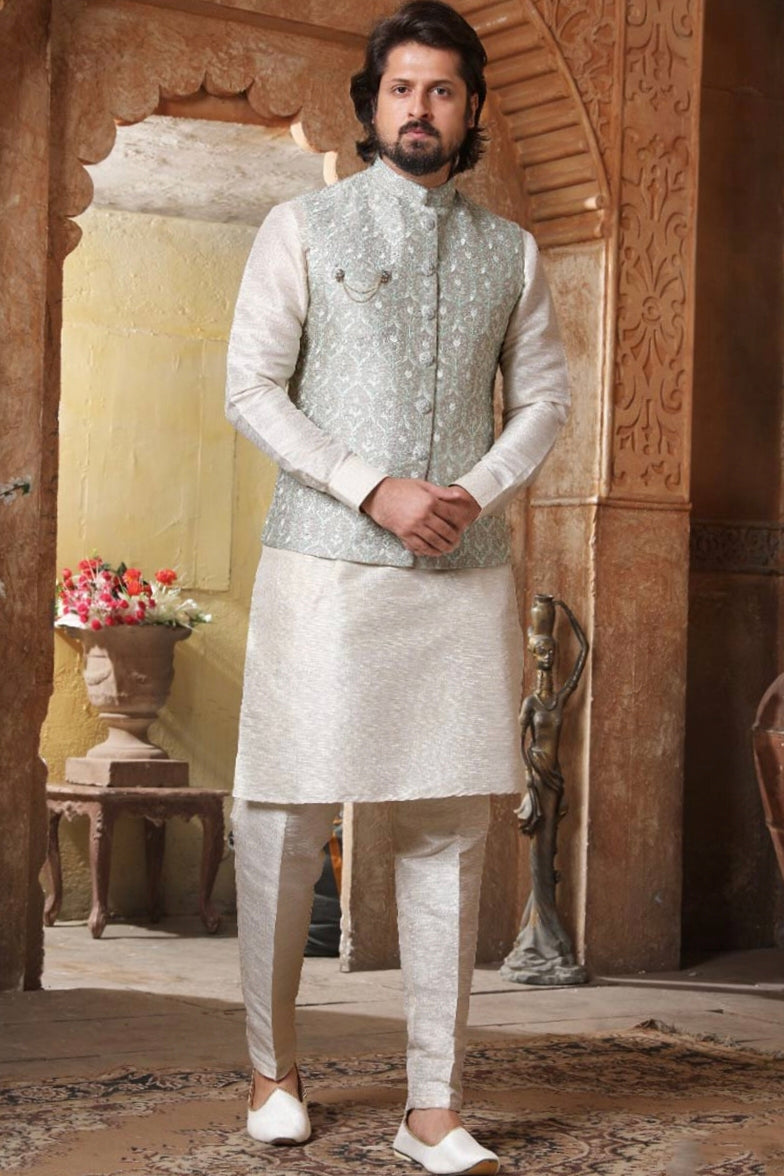 Engagement white dress for men featuring embroidered Nehru jacket with kurta churidar set