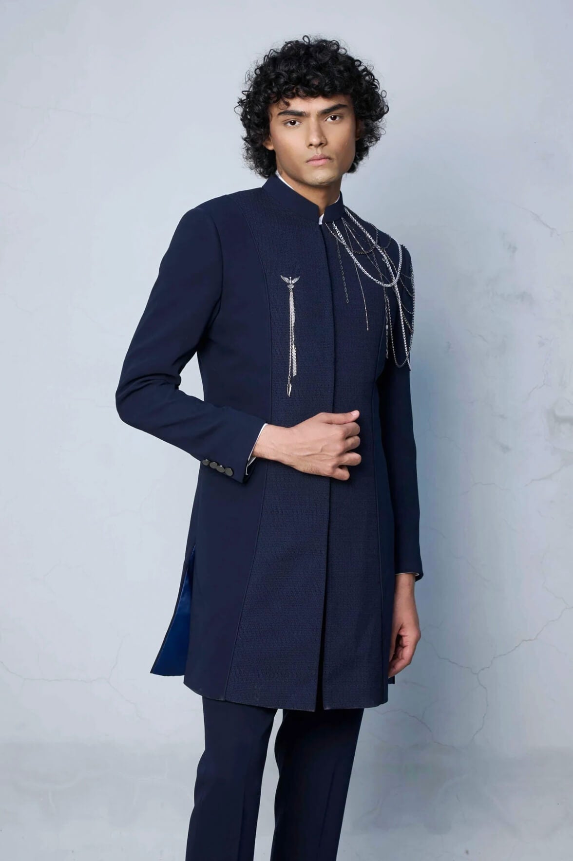 Male model wearing Gargee Designer's blue indowestern jacket with draped metal chain detailing and matching blue pants