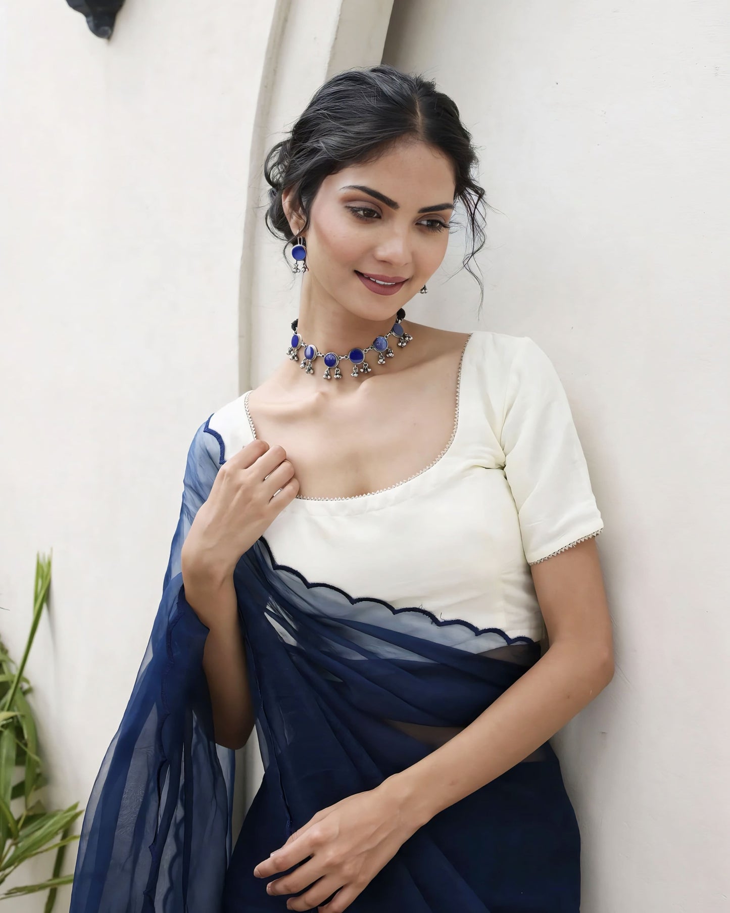 Ivory square neck blouse with short sleeves paired with navy blue scalloped organza saree pallu for elegant festive wear