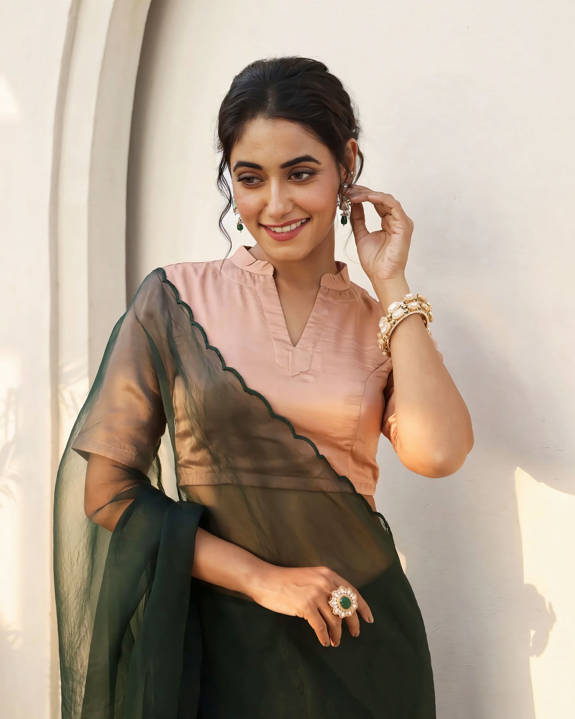 Peach princess cut blouse with notched neckline and dark green sheer pallu styled for festive saree wear
