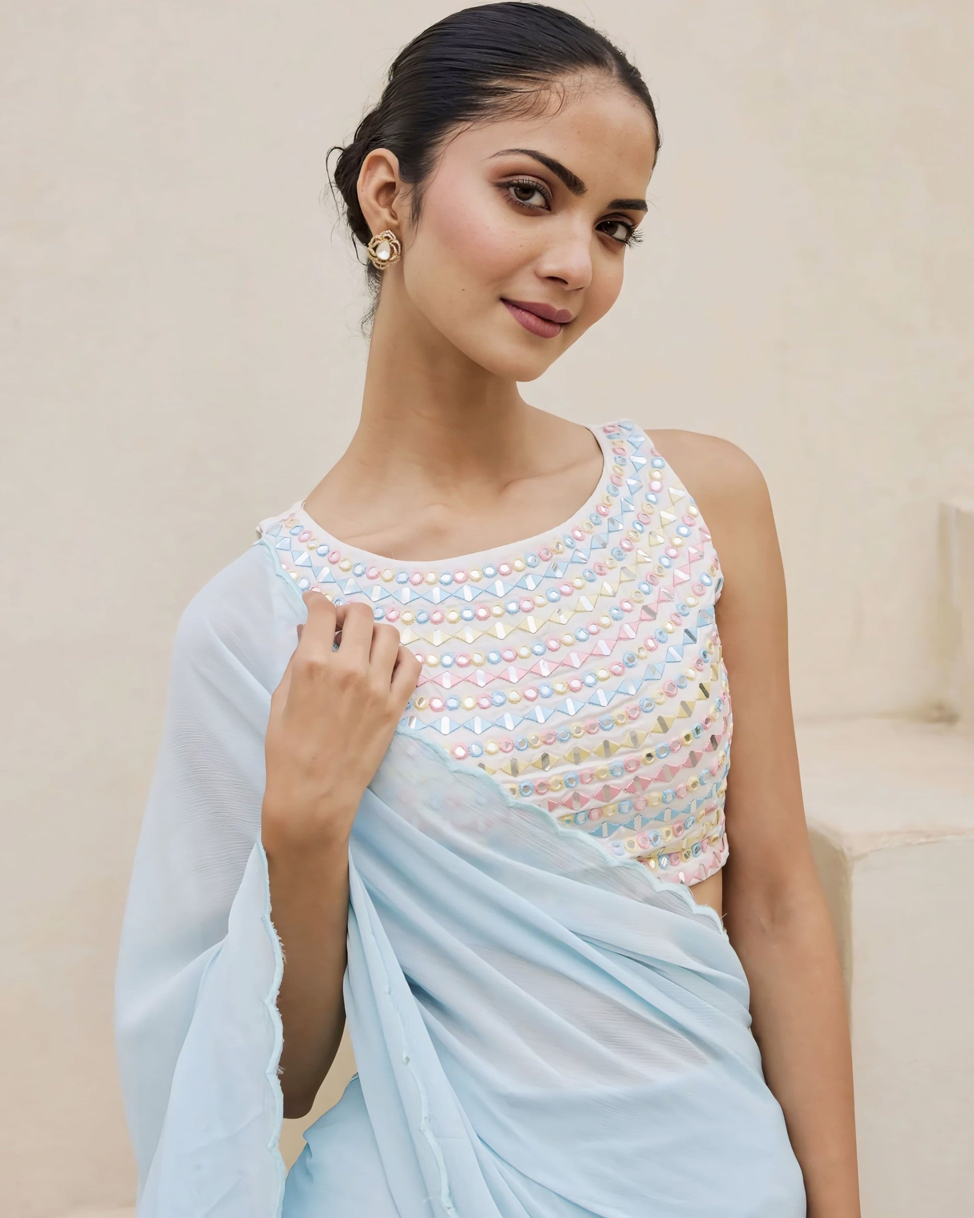 Pastel mirror work princess cut sleeveless blouse with round neckline paired with a light blue saree