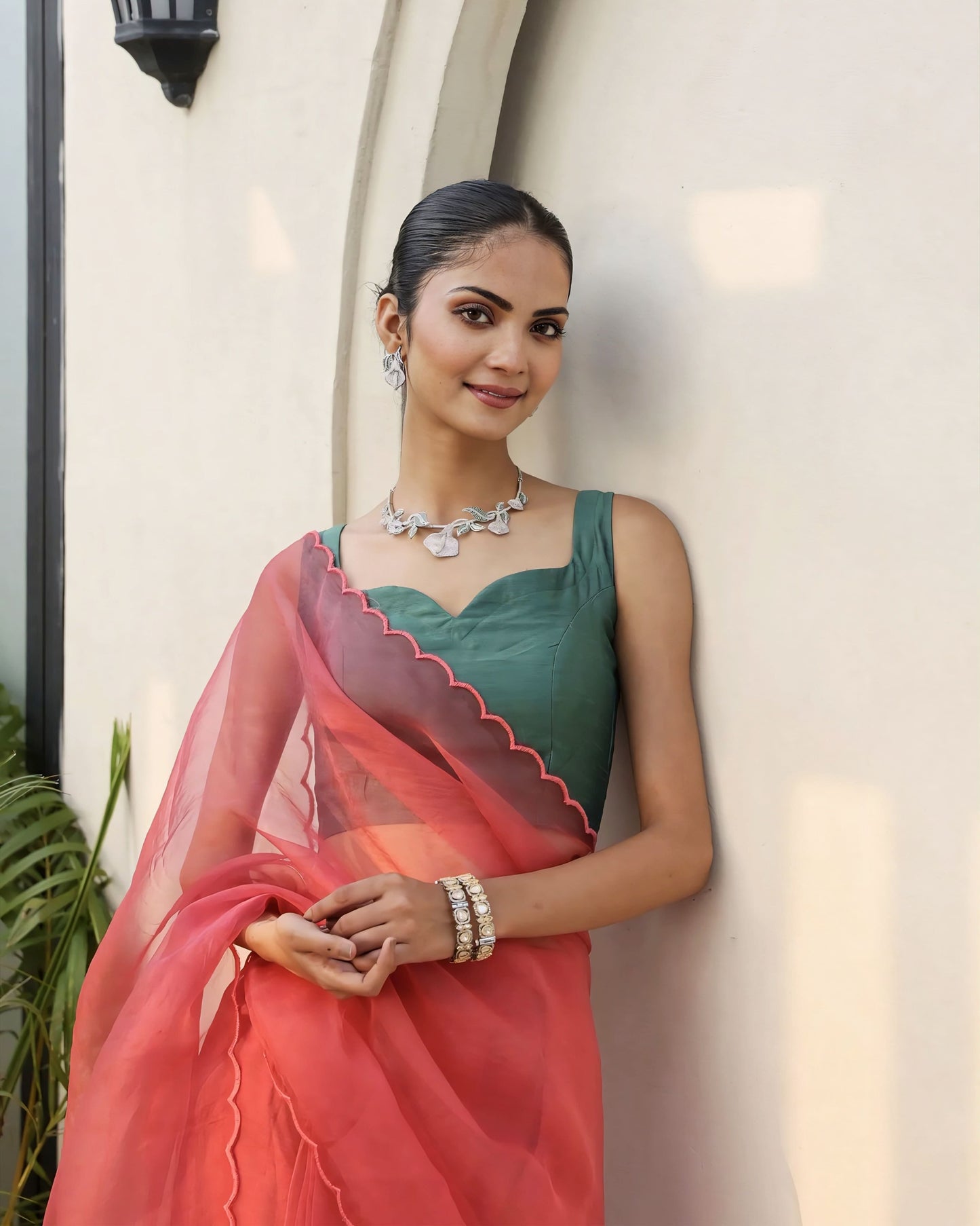 Emerald green princess cut sleeveless blouse with sweetheart neckline paired with a red sheer saree