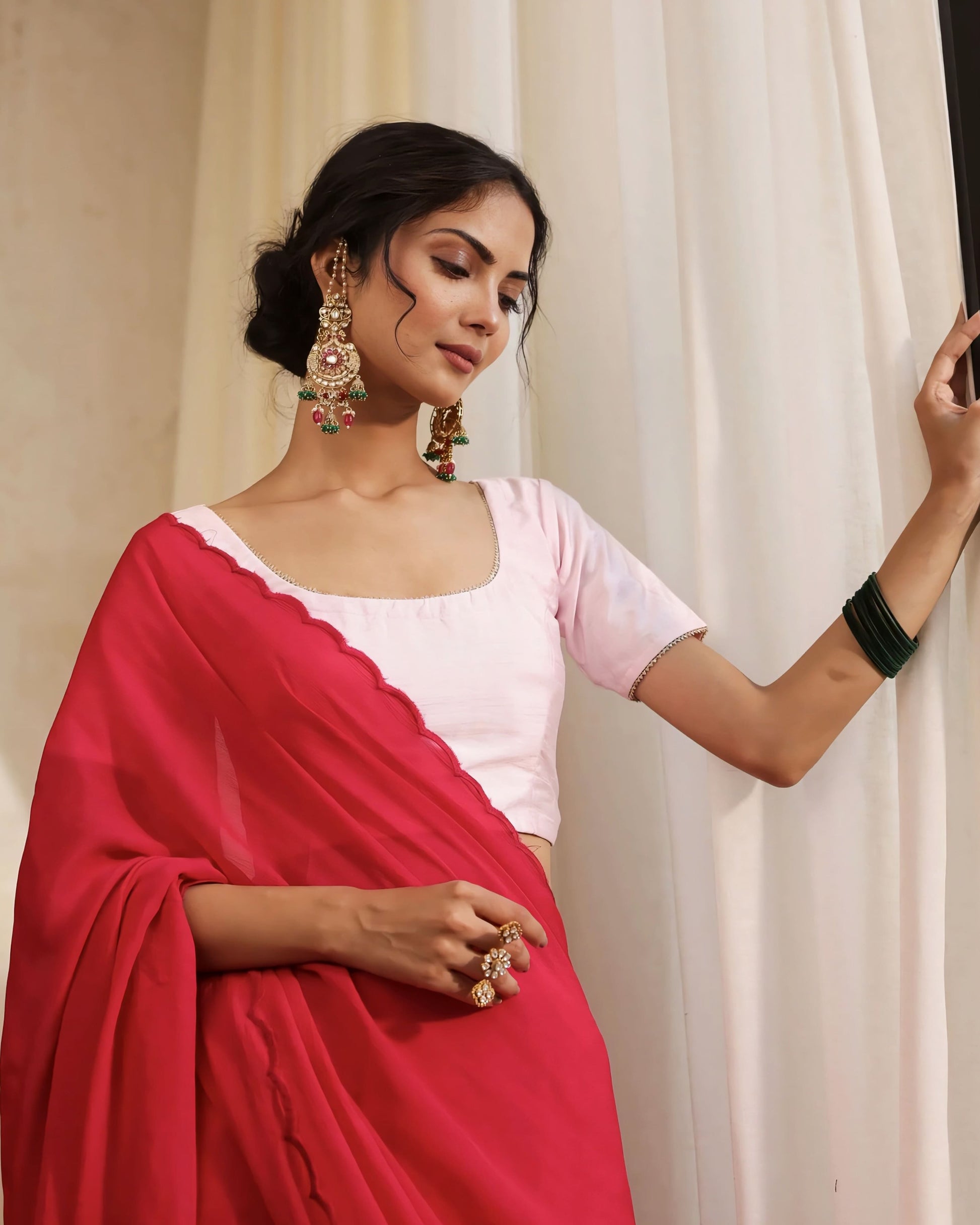 Blush pink princess cut blouse with scoop neckline and short sleeves paired with a red saree