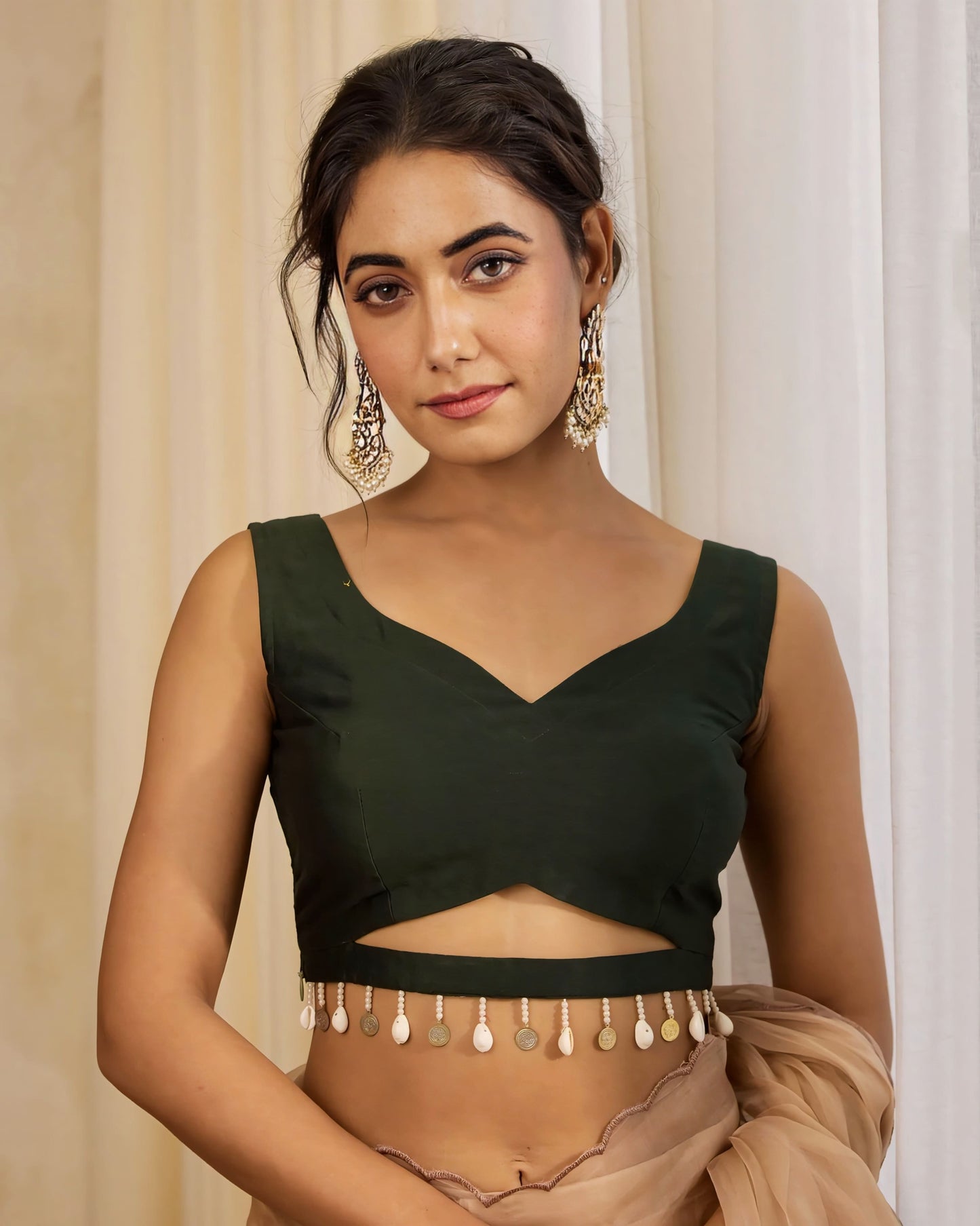 Dark green V-neck cutout blouse with pearl and coin tassel hem paired with beige saree