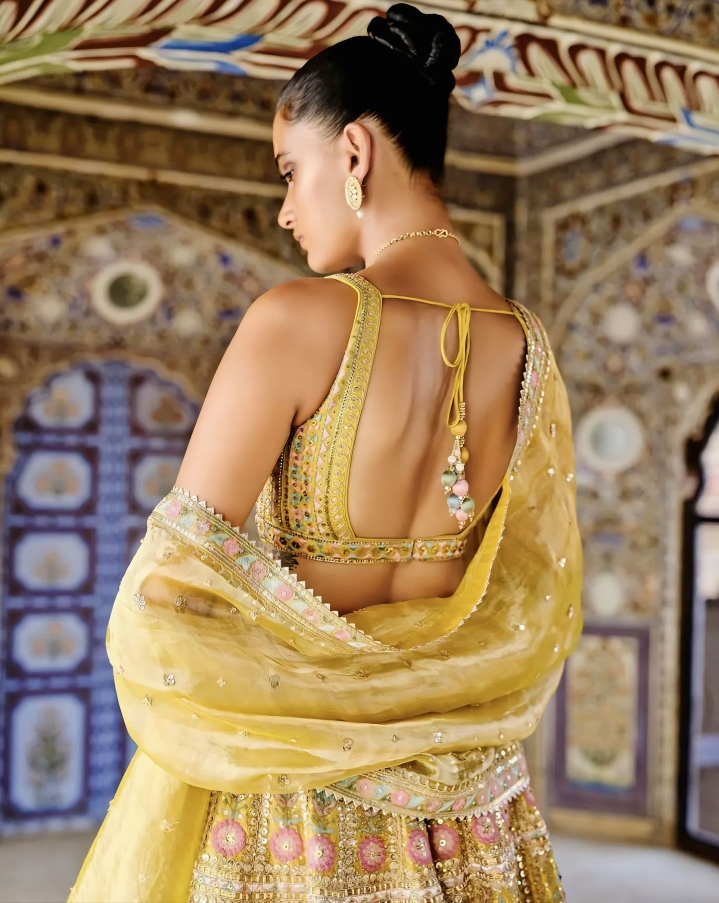 Yellow princess cut blouse with deep back neckline and tie up dori detailing for festive wear