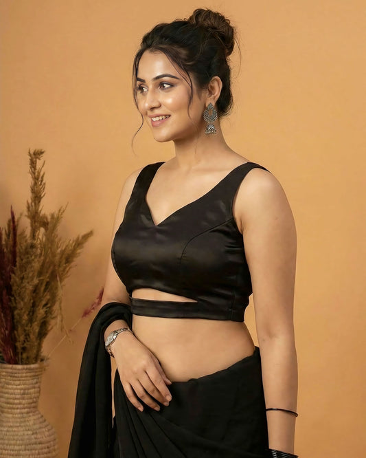 Black satin fancy blouse design with sleeveless V neckline styled for party and wedding saree wear.