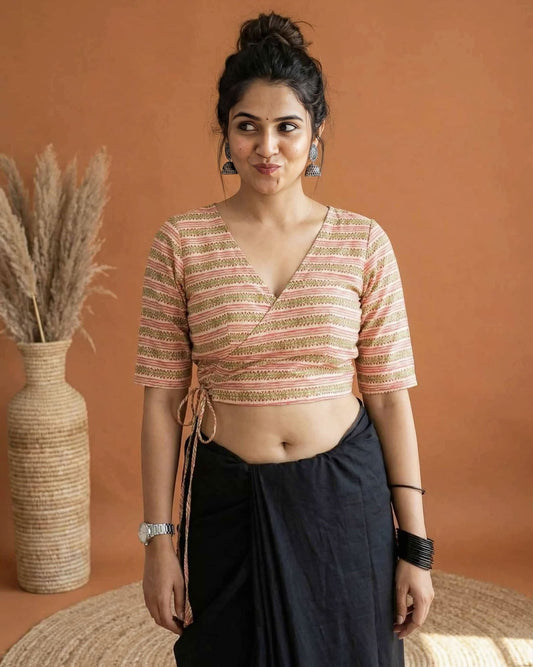Peach angrakha style blouse with wrap tie-up design and V neckline paired with black saree for festive wear.