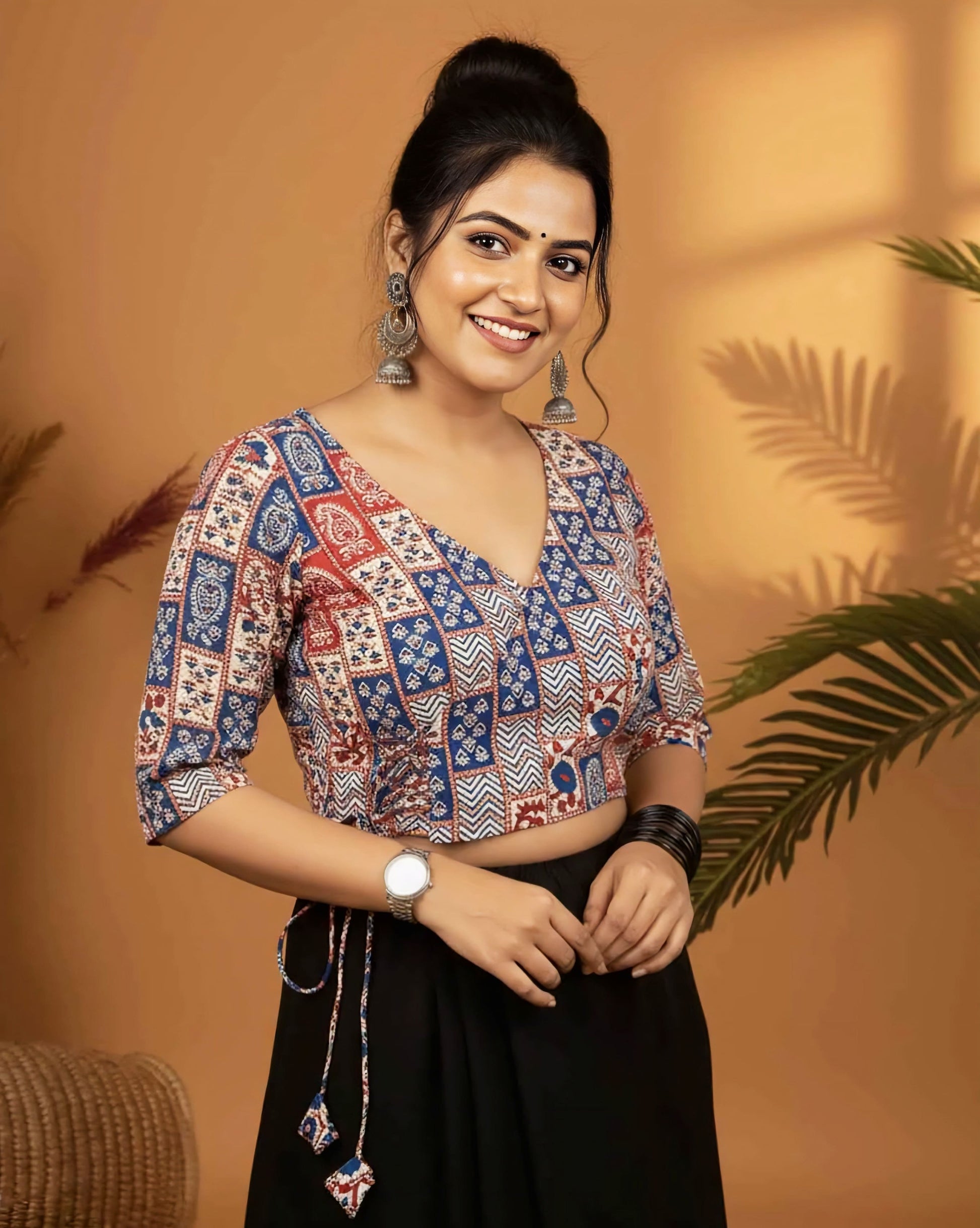 Red and blue printed angrakha style blouse with side tie-up tassels and V neckline paired with black saree.