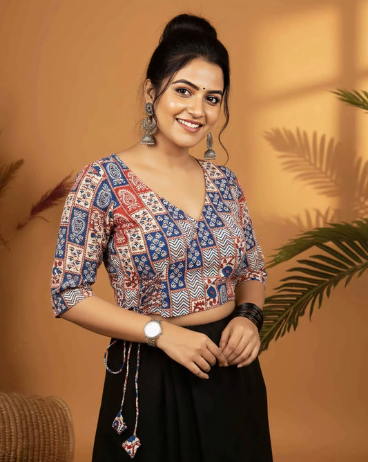 Red and blue printed angrakha style blouse with side tie-up tassels and V neckline paired with black saree.