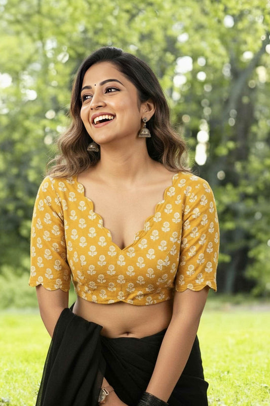 Mustard yellow printed fancy blouse design with scallop neckline paired with black saree.