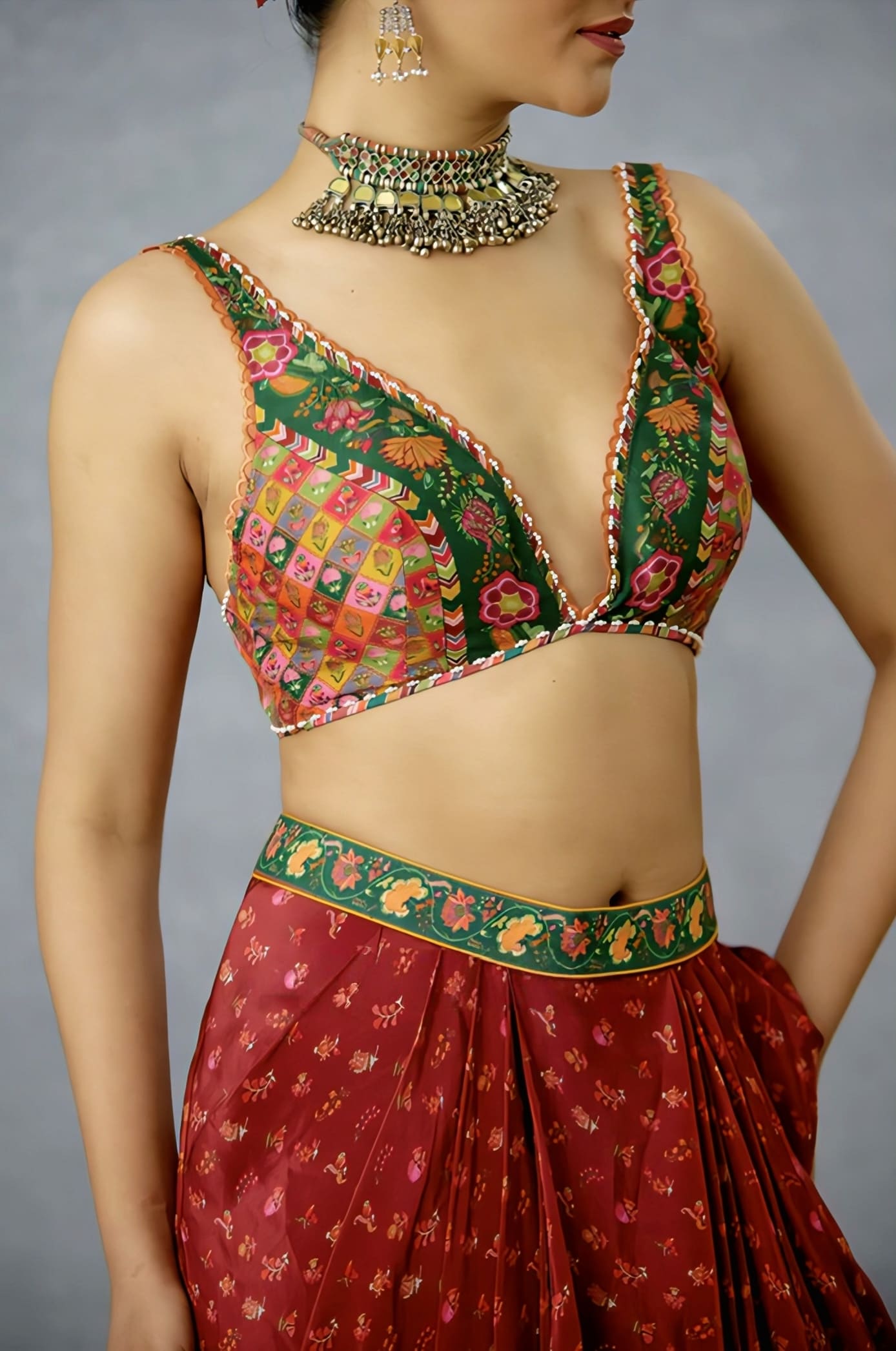 Green patchwork saree blouse with deep V neckline and multicolor embroidery paired with festive saree.