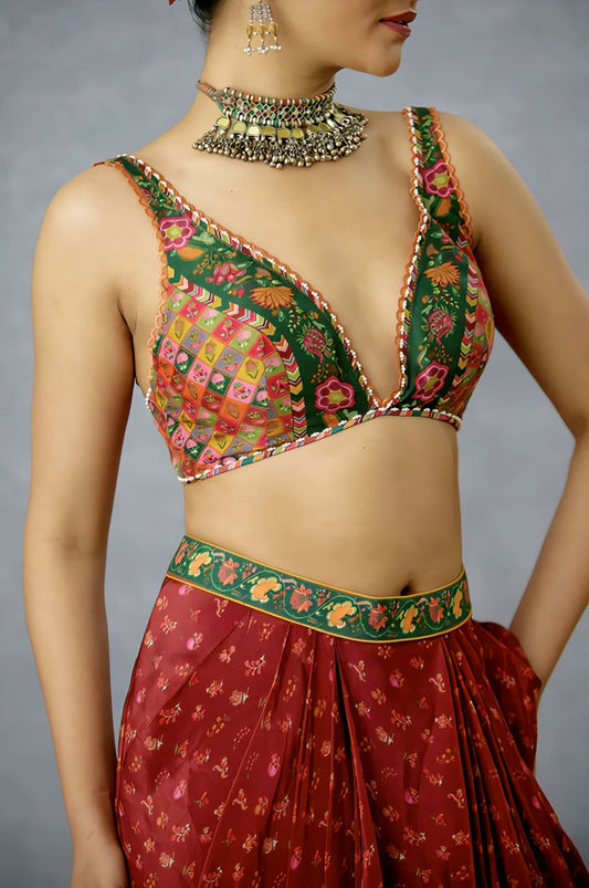 Green patchwork saree blouse with deep V neckline and multicolor embroidery paired with festive saree.