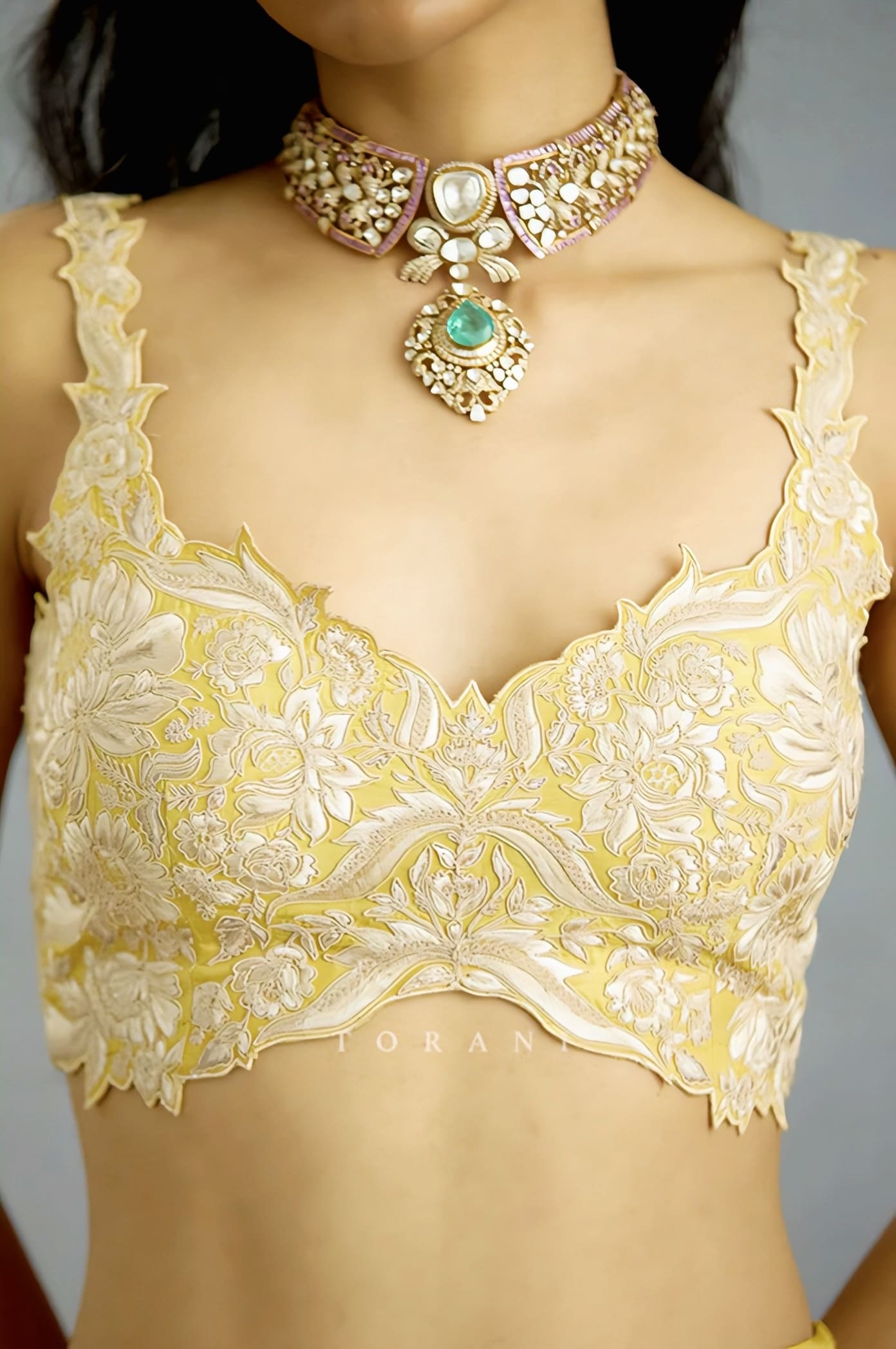 Yellow floral embroidered saree blouse with scalloped hem and intricate ivory threadwork for festive wear.