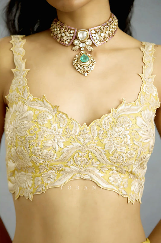 Yellow floral embroidered saree blouse with scalloped hem and intricate ivory threadwork for festive wear.