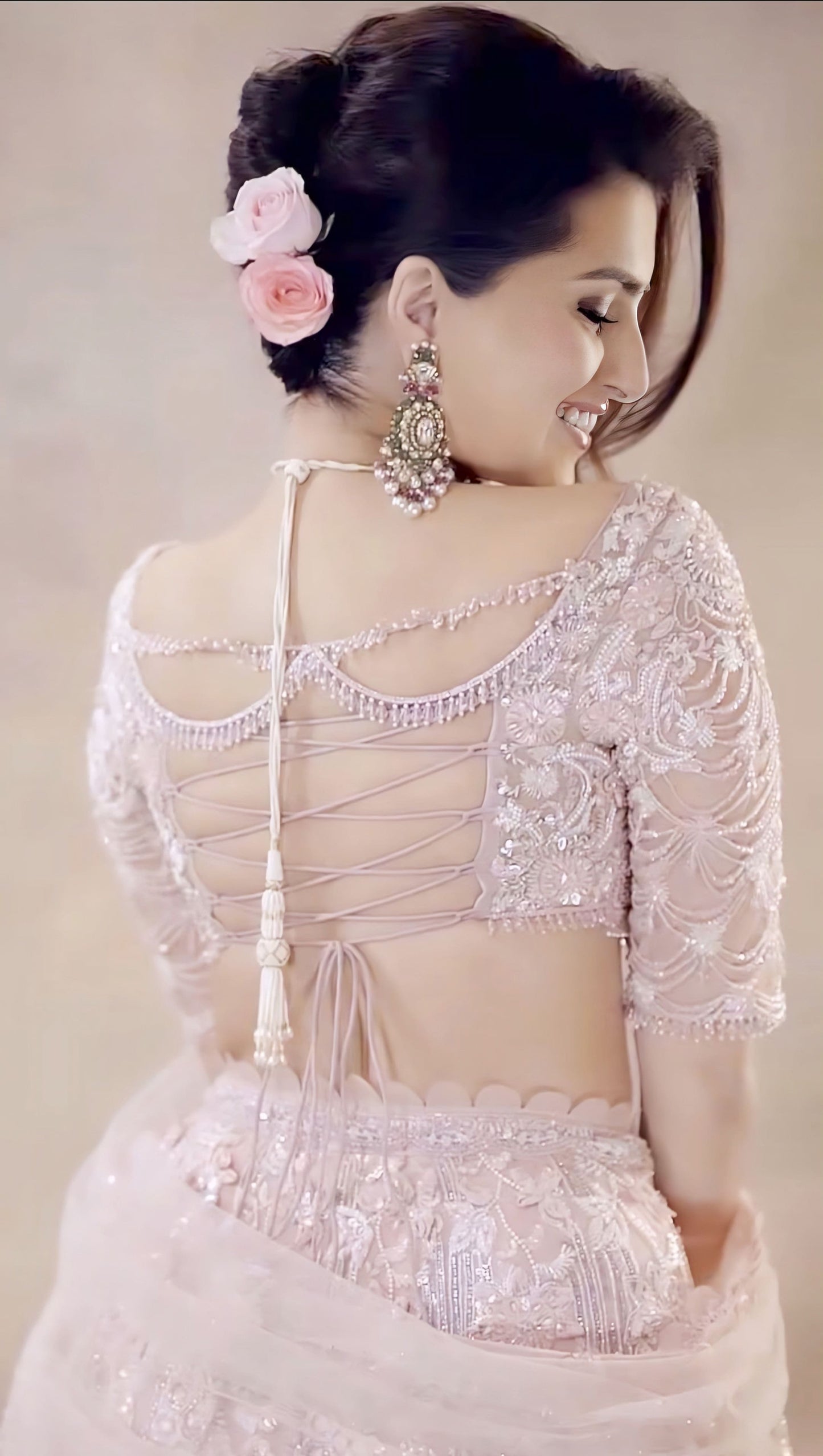 Elegant fancy blouse back design with lace-up tie pattern and intricate embroidery paired with soft pink bridal outfit