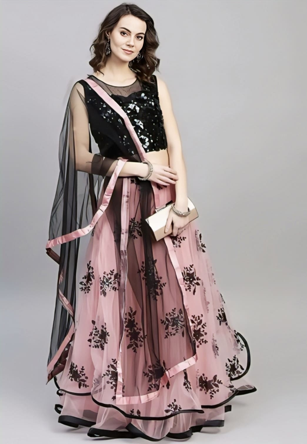 Woman wearing elegant pink lehenga with black sequin blouse and sheer black dupatta for party wear ethnic fashion.