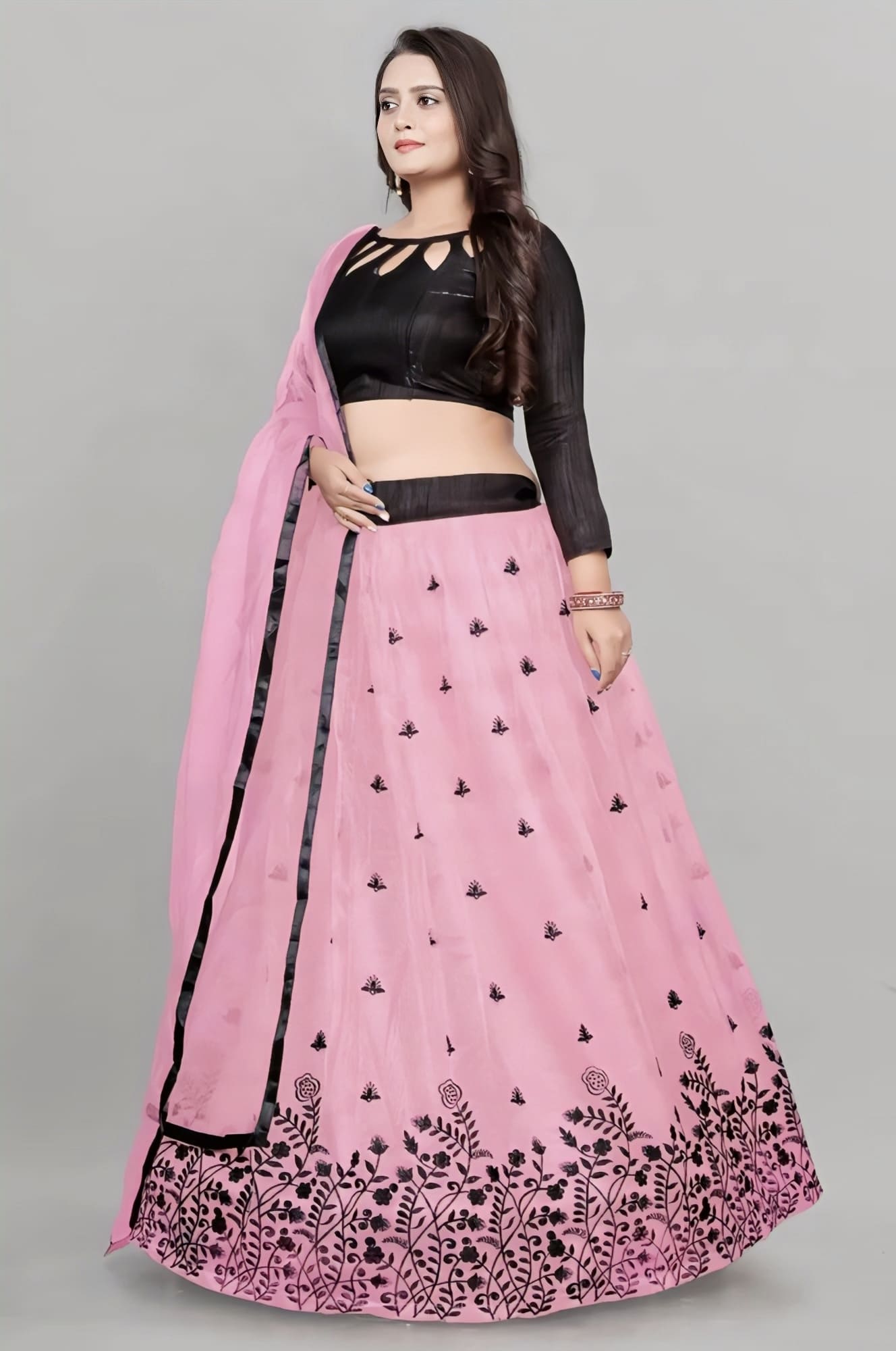 Woman wearing black designer blouse with pink embroidered lehenga and matching dupatta for wedding, festive, and party wear ethnic fashion.