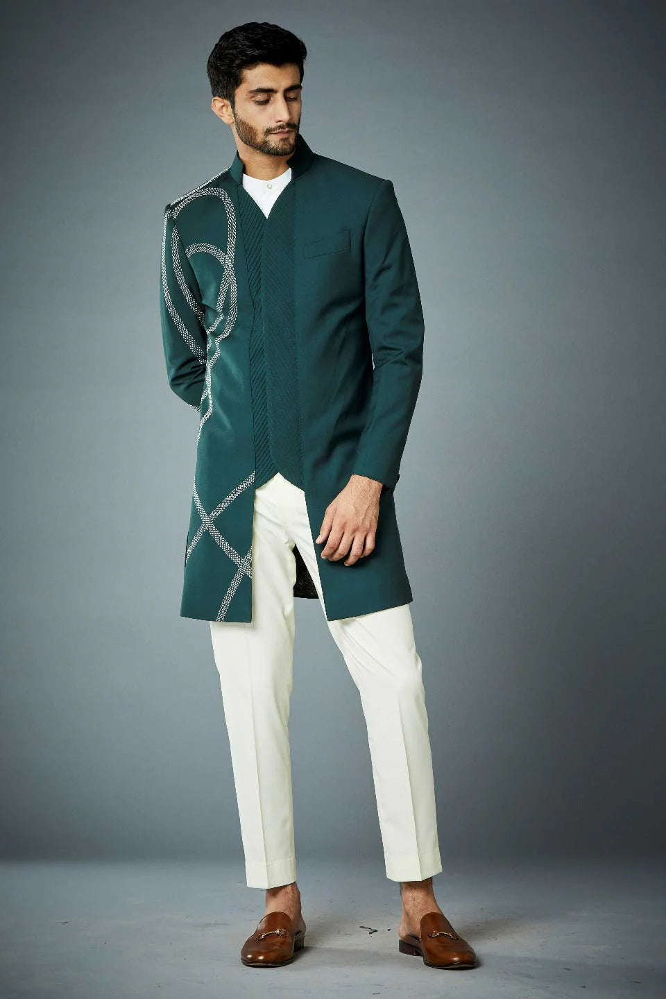 Man wearing modern teal green sherwani for men with geometric threadwork and ivory trousers for a contemporary festive look