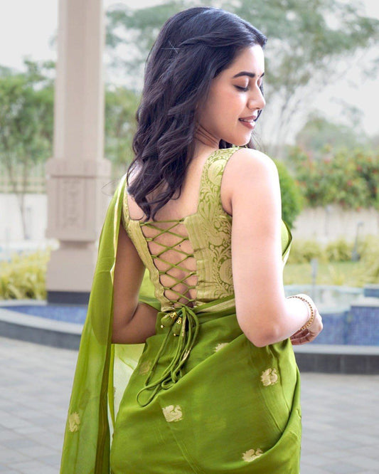 Woman wearing a green traditional outfit with a decorative back design in an outdoor setting.